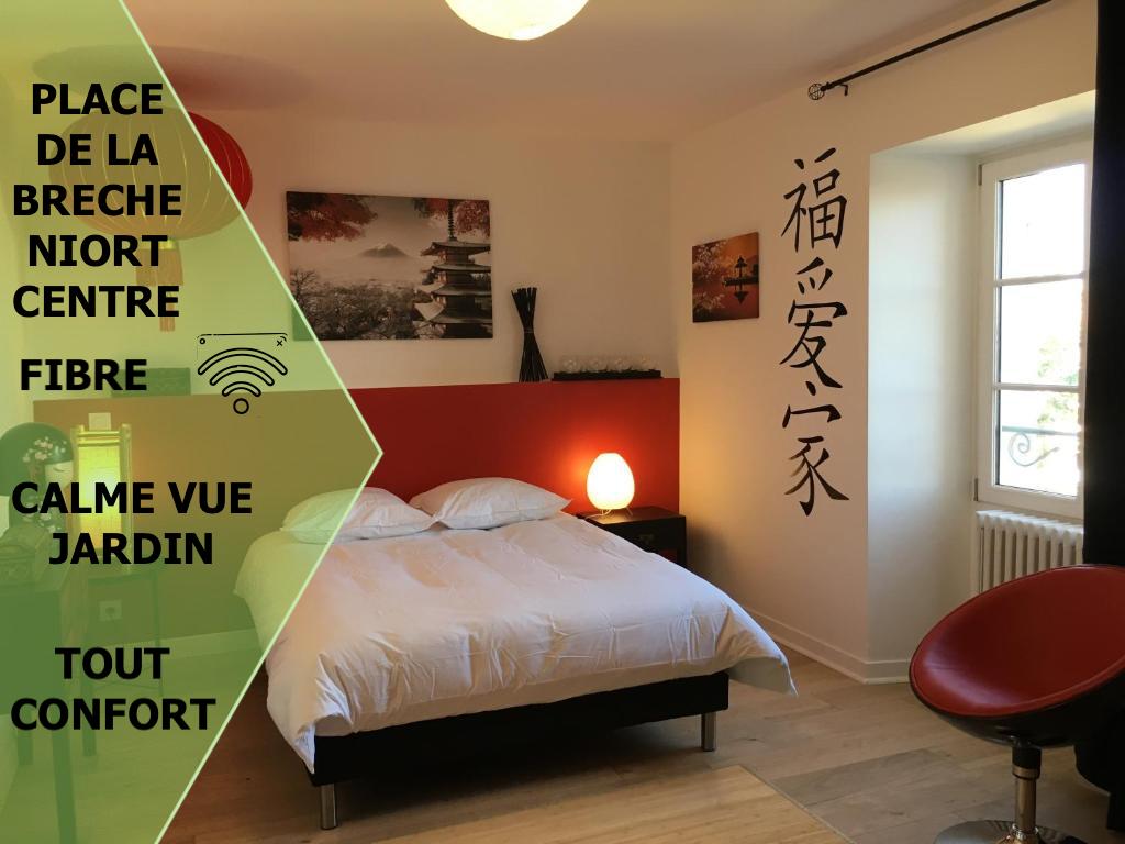 A cozy studio space features a spacious bed with crisp white linens, complemented by a red accent wall. An adjustable lamp glows softly beside the bed. A window overlooks a tranquil garden, while Japanese characters adorn the opposite wall, adding to the serene atmosphere.