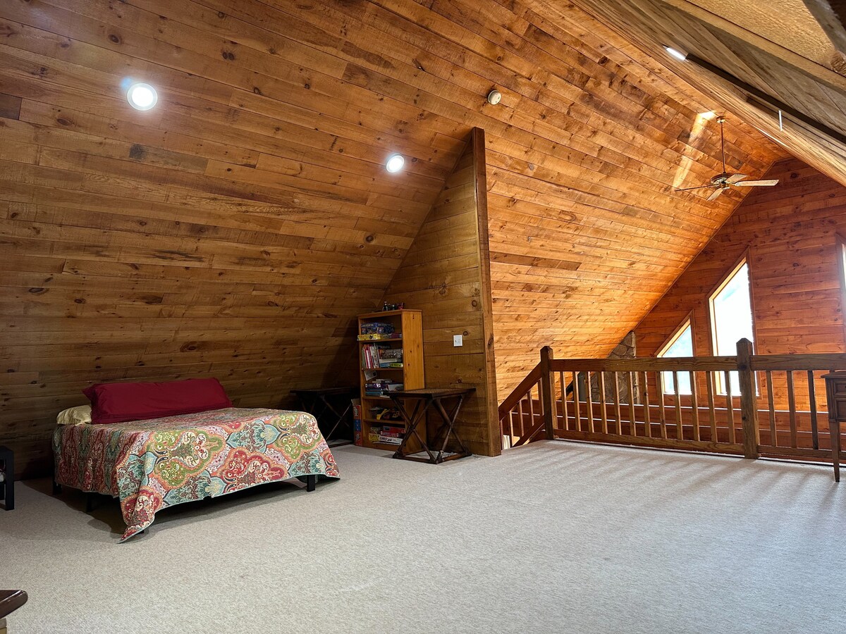 enorme loft en la planta superior con vistas a la sala de estar/cocina con una nueva cama doble, sofá y mucho espacio para jugar y dormir. 