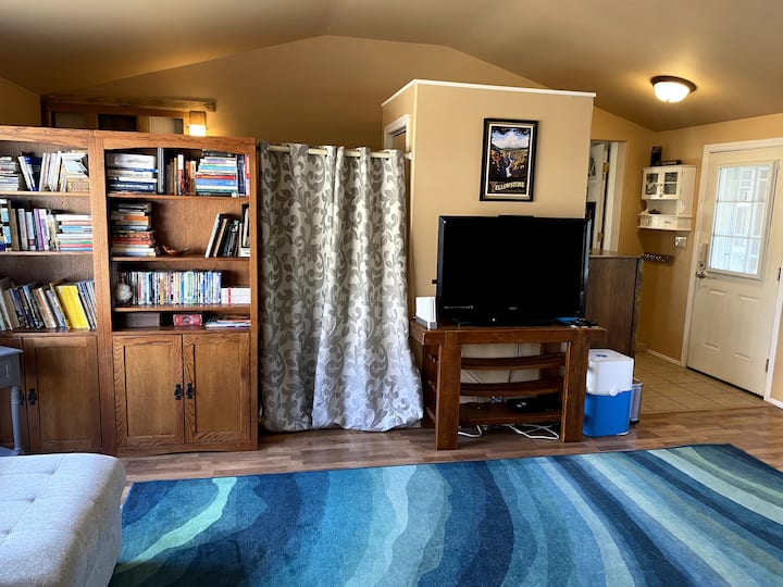 Large living room with view to the nook (left, behind the book shelf), entry door to right, and door into the rest of the house just left of the entry door.