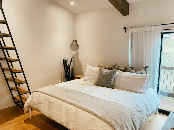 King bed in Master bedroom, with stairs up to king in loft and balcony door to back balcony. 