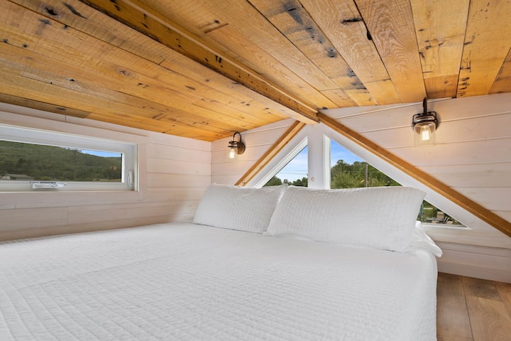 Loftlakás kilátással a hegyekre, és egy king méretű, lépcsővel megközelíthető ágy.