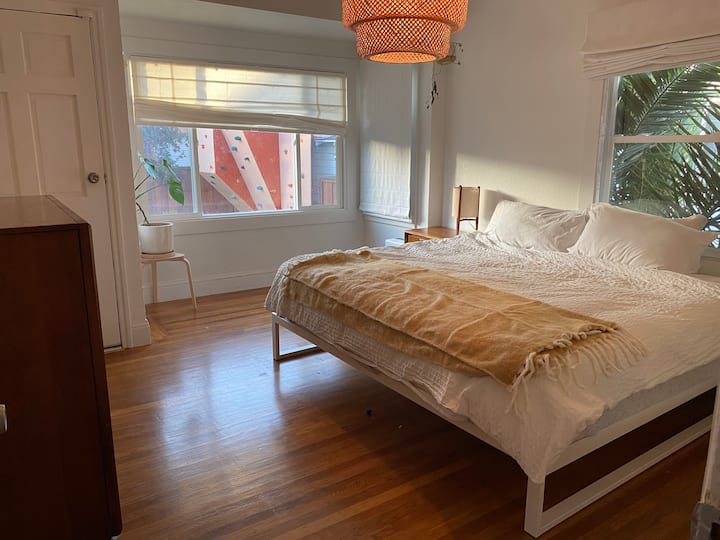 Најголемата спална соба со брачен кревет и врата која води до задниот трем и градината.