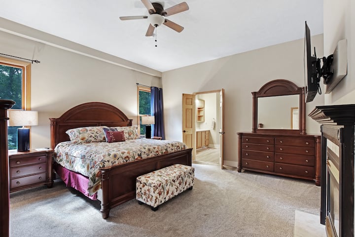 The main floor master bedroom boasts a king-size bed, 40" HD Smart TV, and a fireplace. Also, enjoy the huge en-suite bathroom with Jacuzzi tub.