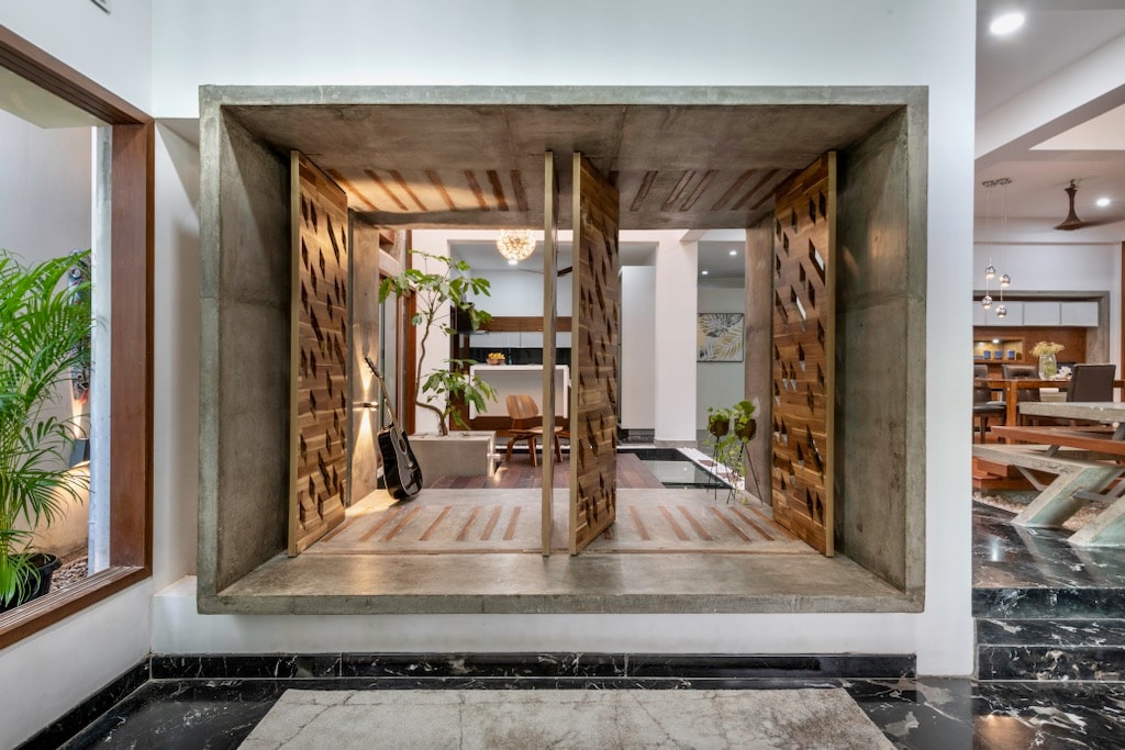 A unique feature of the villa is displayed, showcasing a modern window design with wooden slatted shutters. The open shutters reveal a glimpse of greenery and seating, enhancing the connection between indoor and outdoor spaces.