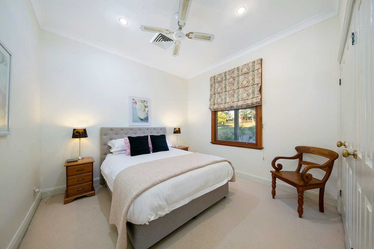 Queen bedroom 2 with bedside tables, lamps, chair and built in robe 