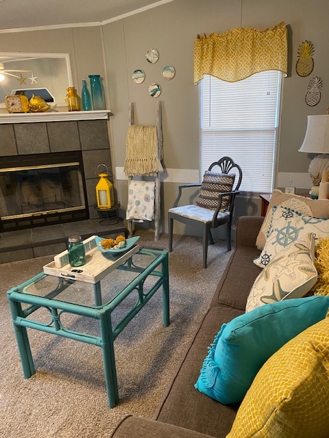 A cozy living area features a gray sofa adorned with colorful cushions, including turquoise and yellow. A teal coffee table sits at the center, accompanied by snacks and drinks. A decorative fireplace and wall art enhance the coastal theme, while natural light filters in through the window.
