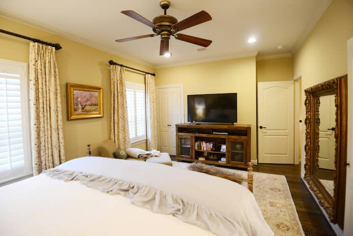 Grande télévision connectée, placard à gauche de la télévision, chaise avec ottoman 