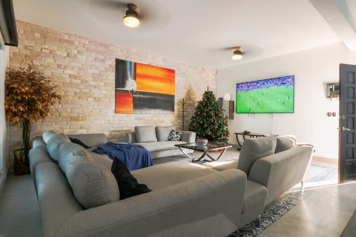 En la sala hay dos sillones tamaño cama matrimonial y una pantalla de 86"