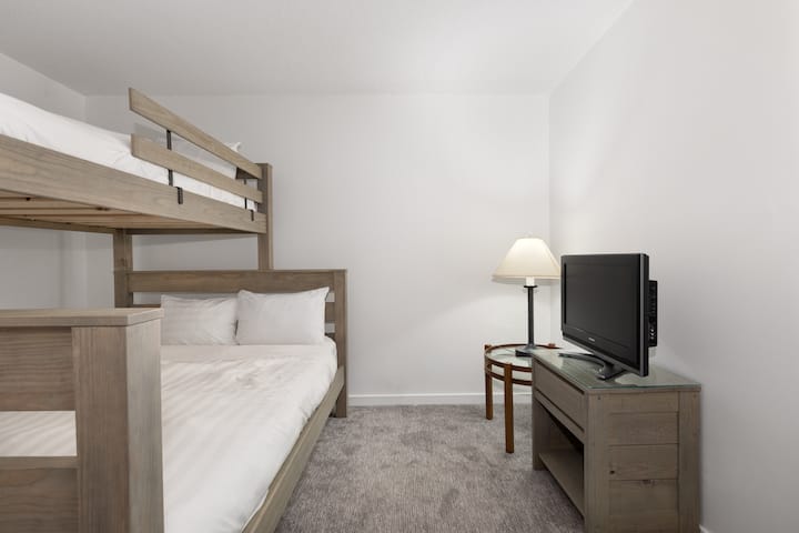 Tercera habitación con litera: cama doble larga en la parte de arriba y queen de abajo. Televisor de pantalla plana.