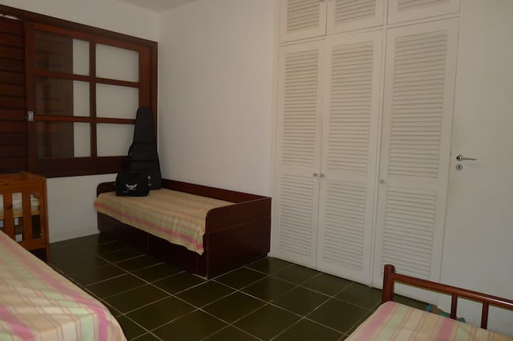 غرفة نوم بها 3 أسرّة فردية وسرير أطفال ونافذة كبيرة ومروحة سقف وخزانة ملابس مدمجة وما إلى ذلك.