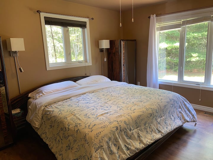 ห้องนอนใหญ่พร้อมเตียงคิงไซส์และหน้าต่างบานใหญ่ที่มองเห็นสนามหน้าบ้านส่วนตัว