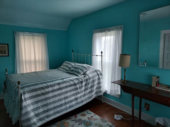 Dormitorio al noreste en planta alta con cama matrimonial y estructura de cama de hierro fundido vintage. 