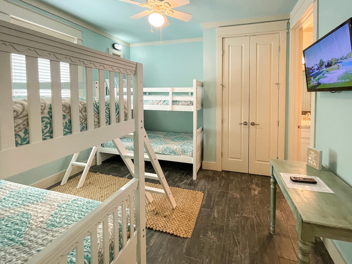 غرفة نوم بطابقين مع إمكانية الدخول إلى حمام مشترك يحتوي على مرآة مزدوجة وحوض استحمام