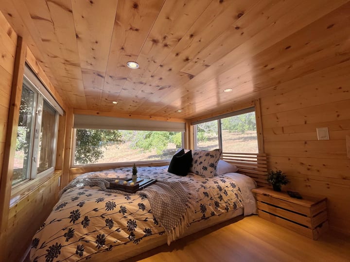 In the master bedroom, you are sleeping amongst the trees! A queen bed makes for a cozy and comfortable space with still plenty of room to get around. Amazing view of the stars on clear nights. We have seen shooting stars twice now.