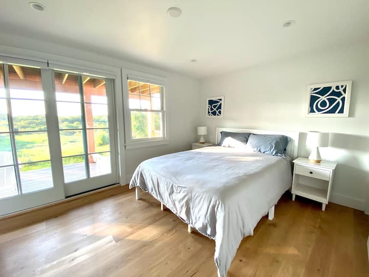 Habitación queen con acceso a la terraza inferior y baño completo privado con ducha a ras de suelo.