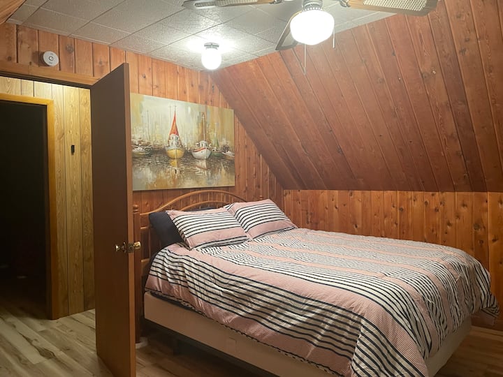 ห้องนอนชั้นบนด้านหน้าพร้อมเตียงขนาดควีนไซส์และโต๊ะทำงานพร้อมวิวทะเลสาบ