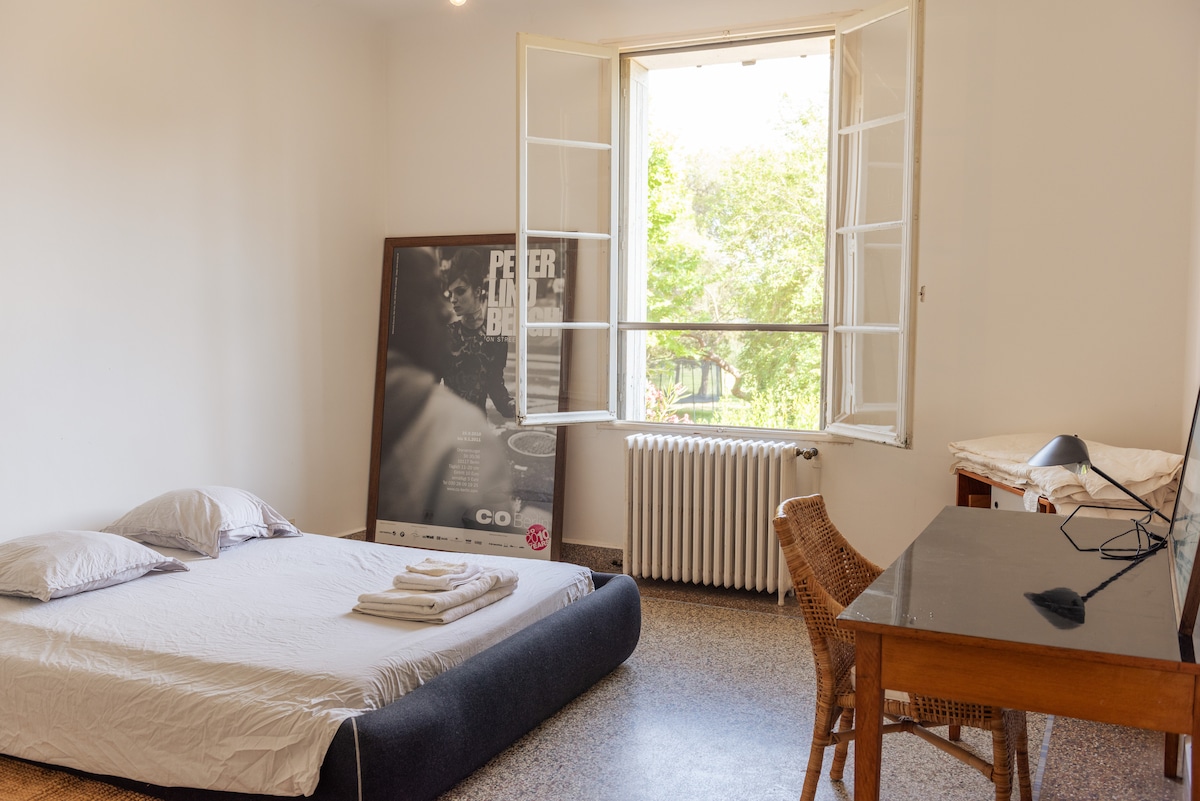 Pogled na sobu s velikim bračnim krevetom, velikim prozorom i radnim stolom