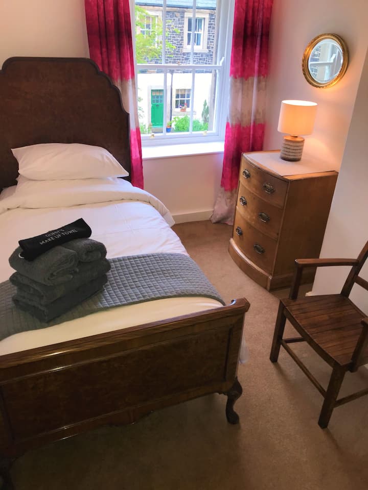 Unser drittes Schlafzimmer mit einem großen Einzelbett bietet einen Blick auf den Gemeinschaftsplatz. 