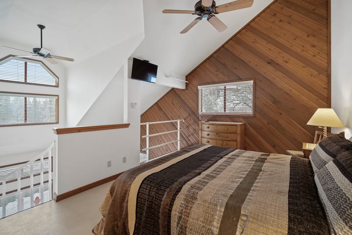 Quarto loft com cama king size, ventilador de teto e muita luz natural, criando um espaço luminoso e arejado para relaxar.