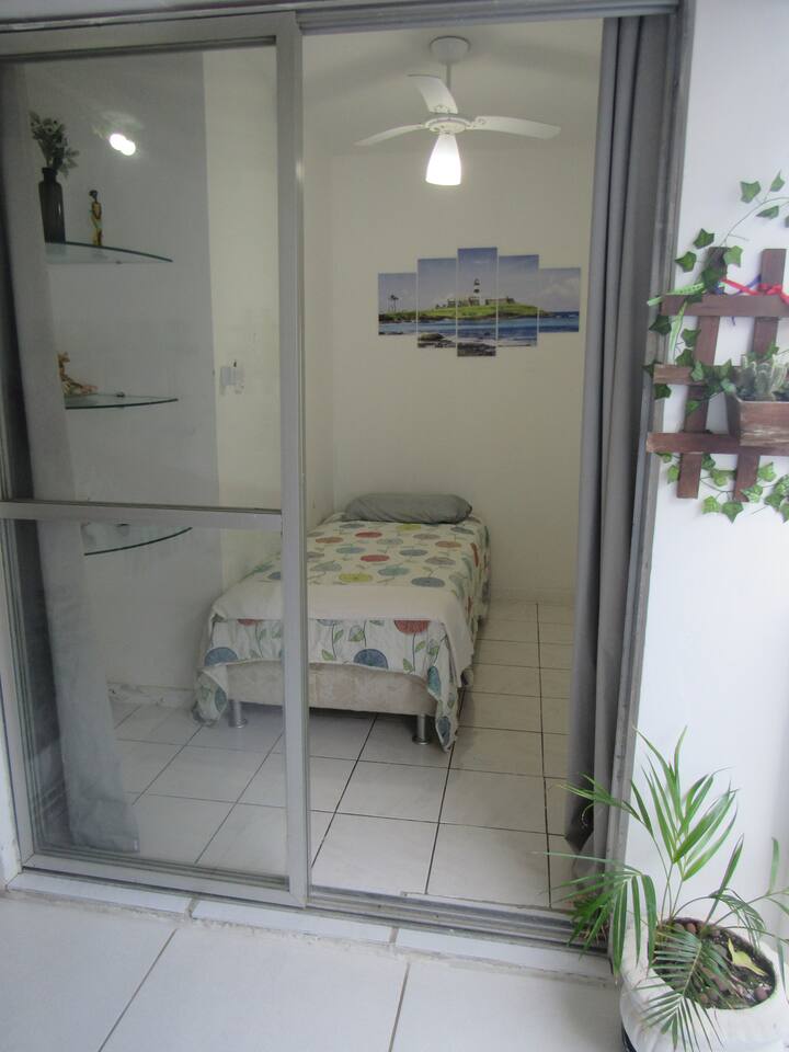 Dormitorio 3: cama individual, ventilador de techo, 3 estantes, volúmenes de puerta/oficina, apagón y tablero decorativo Farol da Barra. Esta habitación está junto al balcón del apartamento.