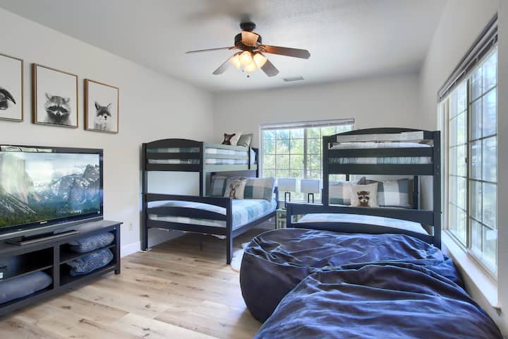 Chambre avec lits superposés avec deux lits simples sur lits doubles, une grande télévision et des poufs jumbo.