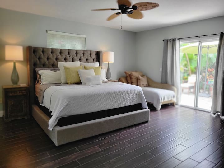 Suite del dormitorio principal con cama tamaño king en el primer piso, armario, puerta corrediza que conduce al patio privado y al jardín.