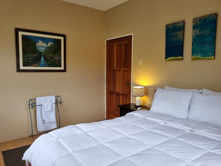 Second upstairs bedroom has a European queen bed (US double bed) and a separate access to the master bathroom. Similar to the master bedroom, this room has blackout curtains. Original local art graces the walls.