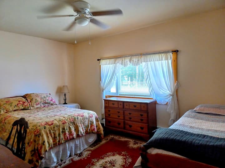 Წინა საძინებელი გზის პირას. Ორადგილიანი საწოლი და ტყუპი საწოლი. Ბიურო და მაგიდა სკამით და საწოლის მაგიდით. ჭერის ვენტილატორი.