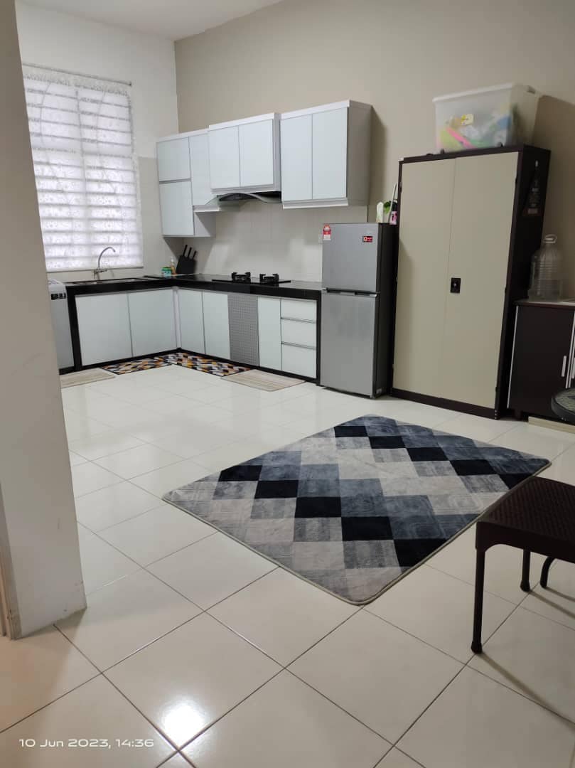 A modern kitchen showcases sleek cabinetry and a spacious countertop. Appliances include a refrigerator and a stovetop. A patterned rug adds warmth to the tiled floor, while a dining table and chairs are positioned nearby, offering a functional and inviting space for meal preparation.