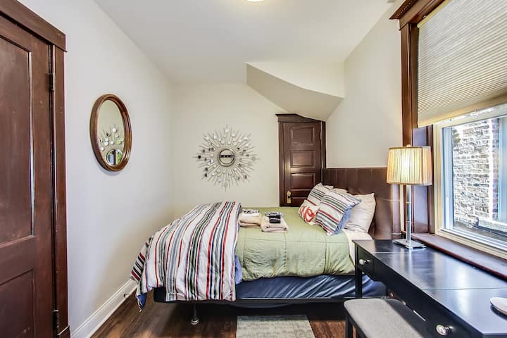 Dormitorio principal con cama tamaño queen, ropa de cama, mantas adicionales, armario grande con perchas de madera, portaequipajes, plancha y mini tabla de planchar. El tocador lateral tiene un banco y un espejo para facilitar la preparación para una noche en la ciudad.