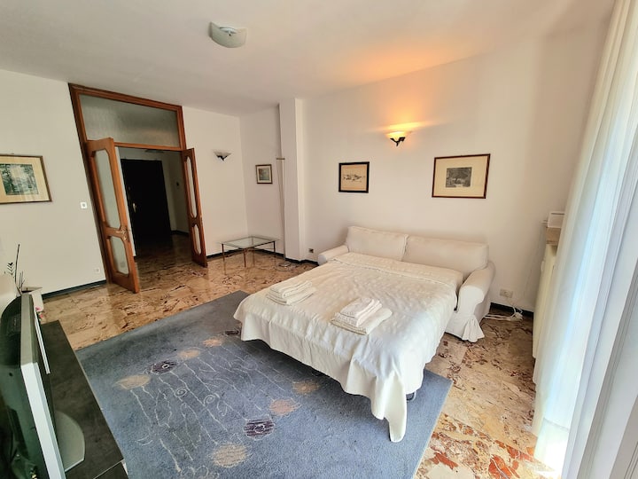 Amplia sala de estar con un cómodo sofá cama, un televisor de pantalla plana y una puerta francesa que ilumina toda la habitación.