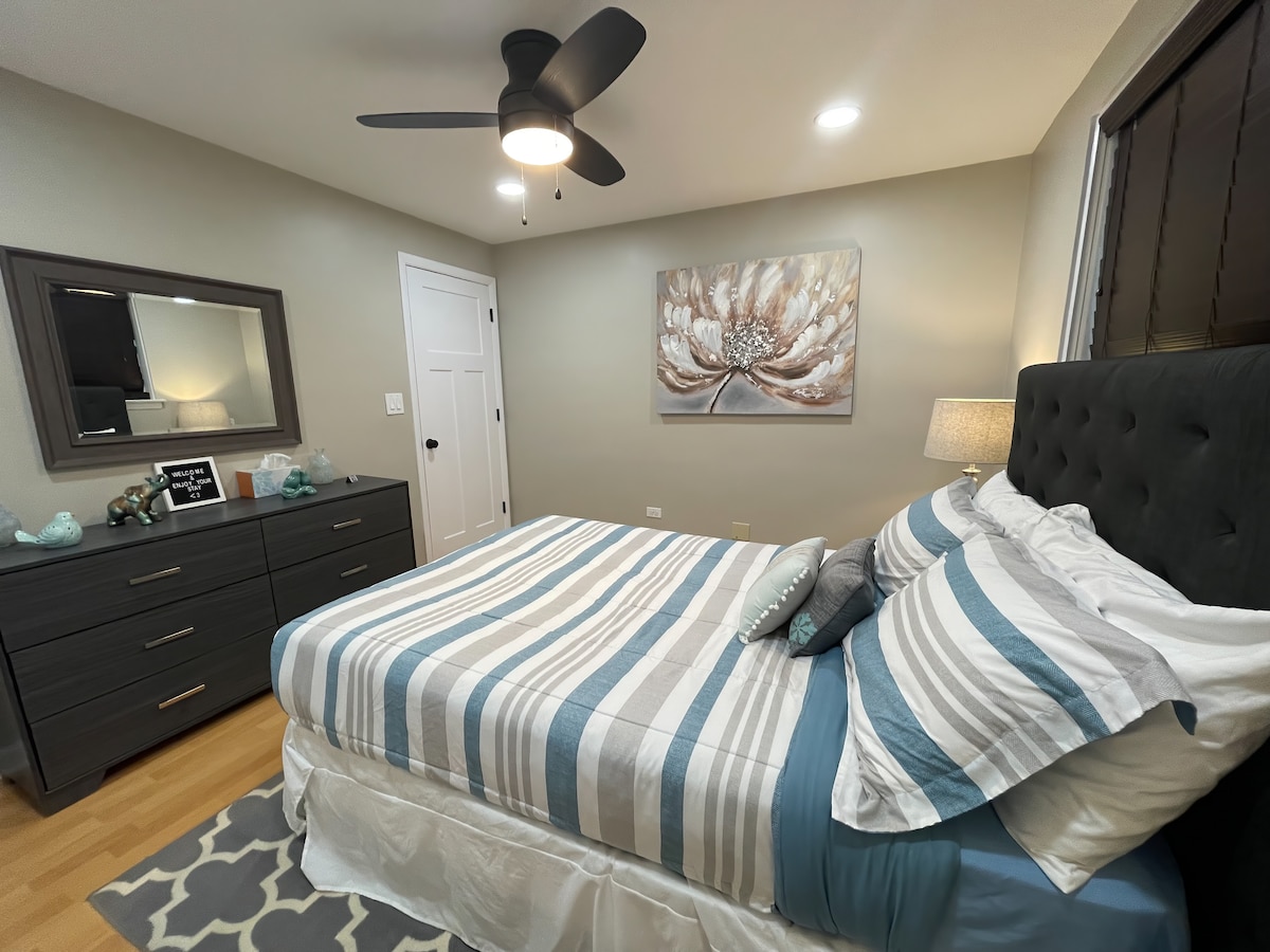 ห้องนอนผู้เข้าพักที่สดใสและอบอุ่นพร้อมพัดลมเพดานที่ทันสมัยแสงอารมณ์หมอนที่สะดวกสบายและผ้าปูที่นอนที่สะอาด