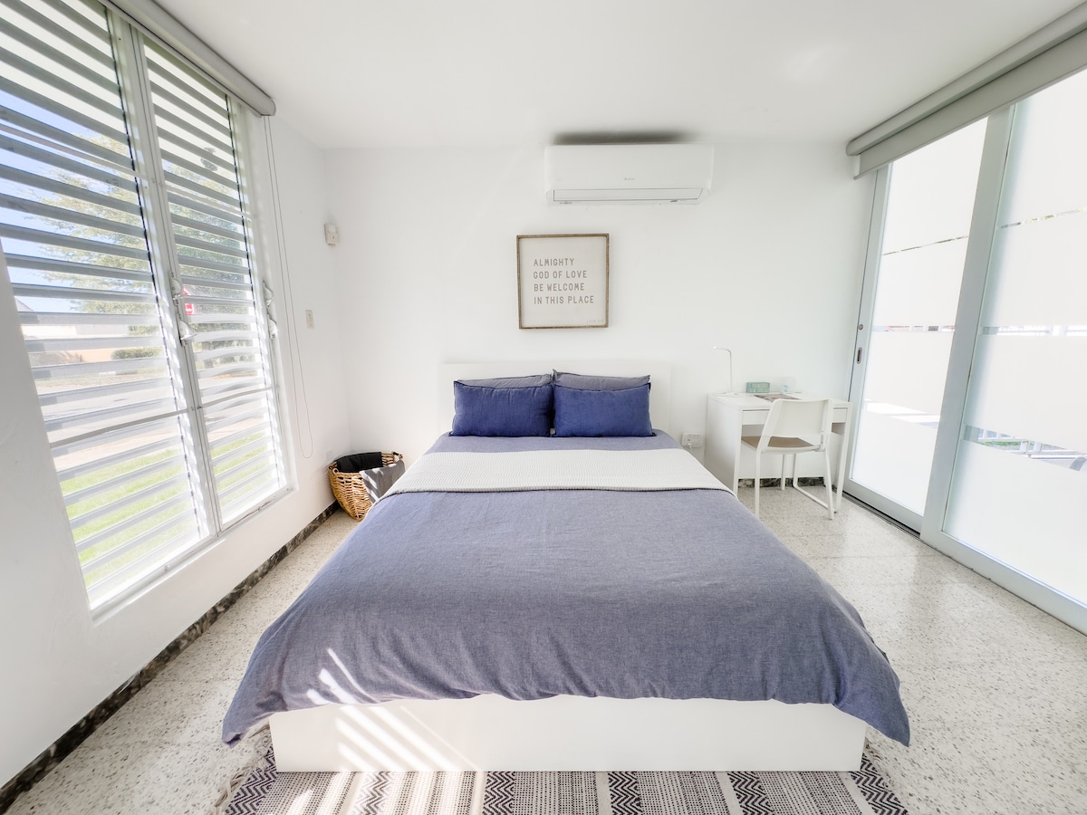 Dormitorio con cama queen size.  Con un escritorio y una silla convenientes.  También otra silla para leer.  