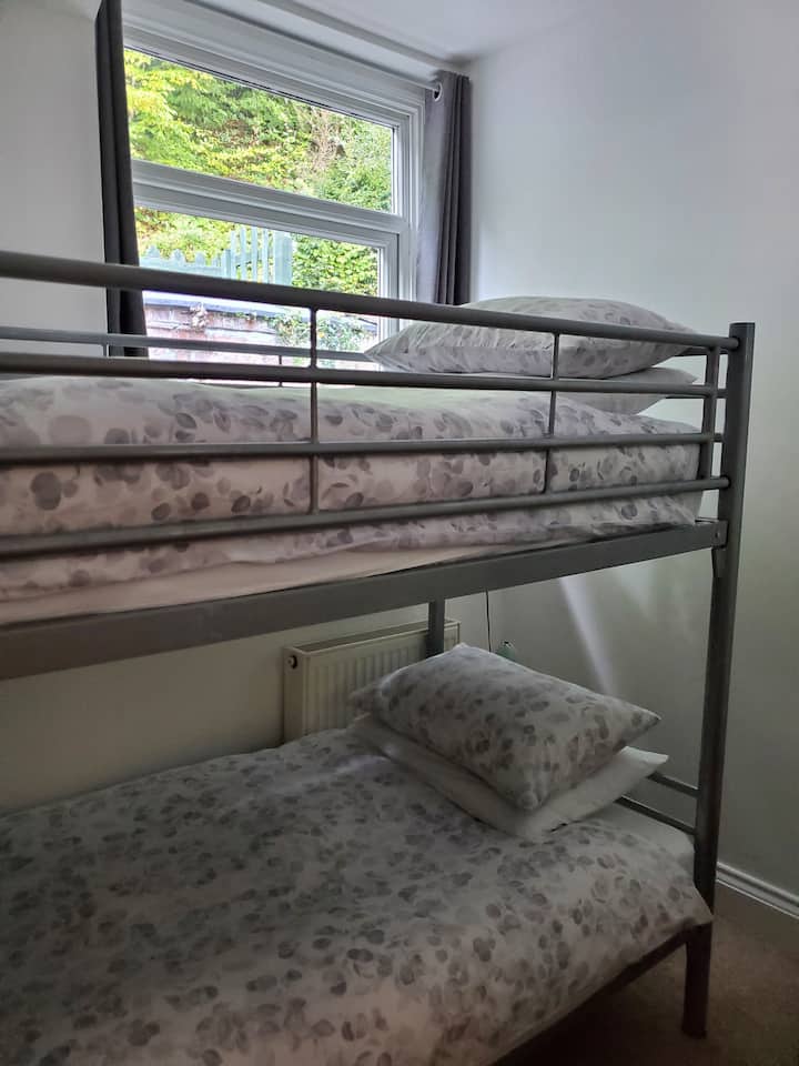 The third bedroom is furnished with single bunk beds, a chest of drawers, chair, mirror and bedside lights