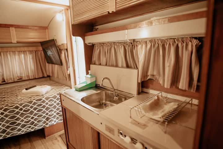 Cozinha funcional: pia, fogão, frigobar, pratos, talheres, taças.