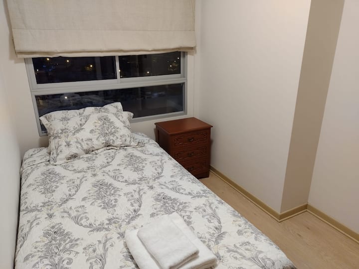 Habitación 2 simple con  closet incorporado, store, ventana con vidrio templado, velador y cama de plaza y media. Sábanas de algodón, ropa de cama de alta calidad y cubrecamas.