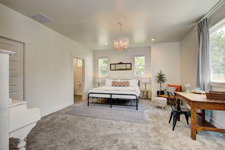 Dormitorio con cama tamaño king, zona de estar, escritorio de oficina, piano y baño privado.