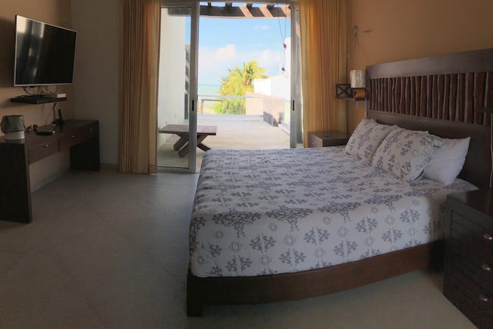 Chumba kikubwa cha kulala chenye
mwonekano wa bahari na mtaro wake, feni na kiyoyozi, Smart TV na saa ya kengele.

Master Bedroom:
Ocean View, mtaro binafsi, AC, dari shabiki, Smart TV na saa ya kengele