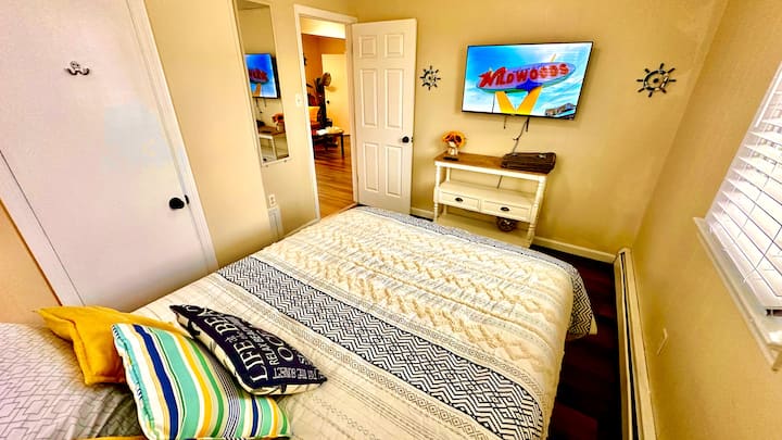 En mysig dubbelsäng i kombination med en 55-tums TV och ett privat badrum, som kombinerar komfort, underhållning och bekvämlighet i en personlig tillflyktsort.