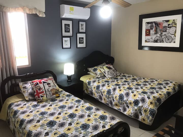 Pomocná spálňa s polovičnými a samostatnými posteľami, odkladacím stolíkom, komodou, televízorom, ventilátorom a klimatizáciou.