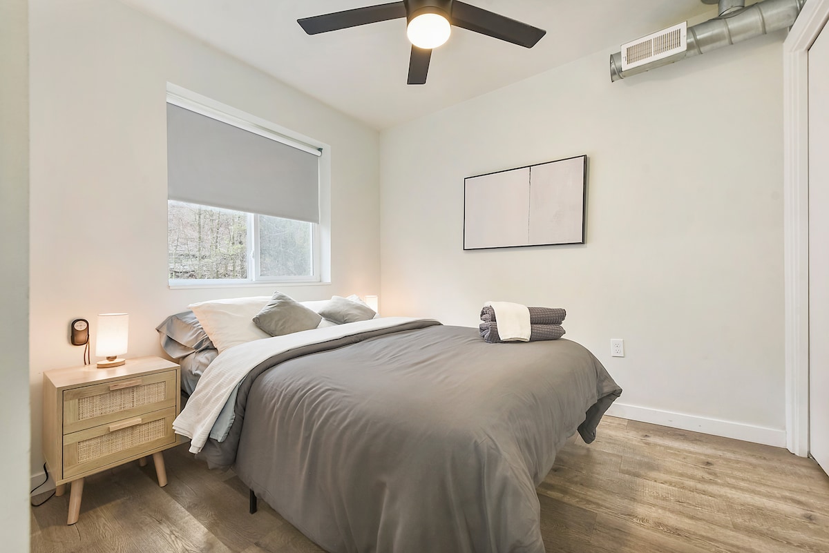 חדר שינה חמים ומזמין עם גוונים אפורים רכים, מרקמים טבעיים ואווירה מרגיעה.