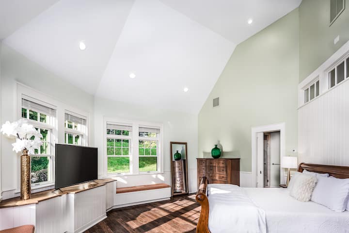 Vue sur la chambre principale de niveau inférieur, qui comprend un plafond voûté, un dressing et une salle de bain attenante avec baignoire à jets.