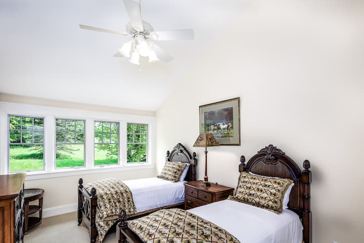 Chambre suite avec lits jumeaux, table de nuit, commode et placard.