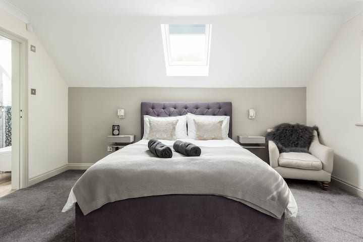 Un dormitorio principal grande y suntuoso con cama tamaño king y lujoso baño privado