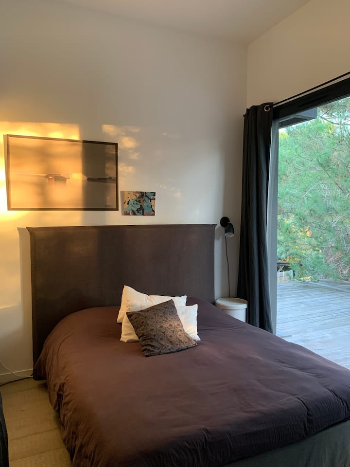 חדר שינה אפור המשקיף על המרפסת והספא. וילונות האפלה. טלוויזיה. ארון ומספרה.