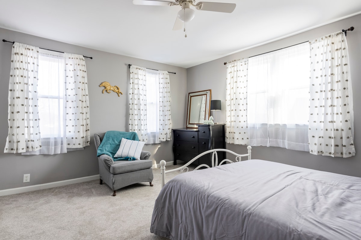 Soba na farmi s jednim bračnim krevetom i udobnom stolicom za čitanje te velikim ormarom i malim komodom.