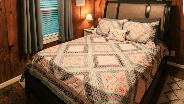 غرفة نوم بسرير متوسط الحجم وتلفزيون ذكي. تبلغ مساحة غرفة النوم هذه 10 × 12 قدمًا.