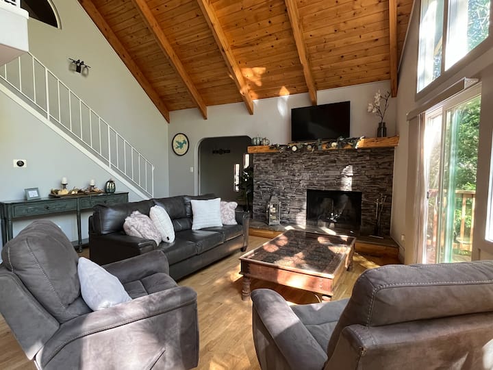 غرفة معيشة في الطابق الرئيسي مع مدفأة وتلفزيون ذكي