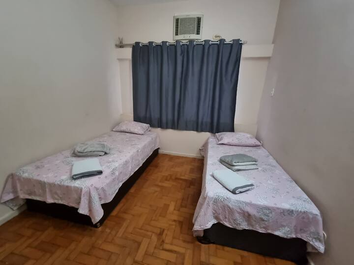 Quarto 2 - Com duas camas de solteiro, com roupa da cama, toalha e coberta e ar condicionado de parede.