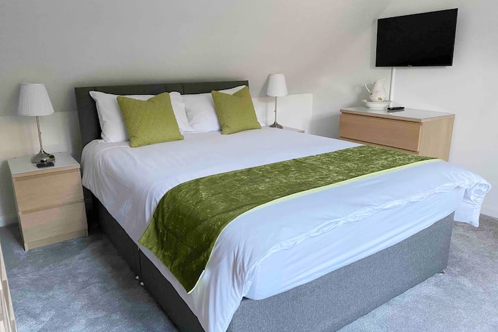 Cette chambre est à l'intérieur. Il dispose d'un grand lit, d'une télévision connectée, d'une armoire ouverte et de nombreux rangements pour tiroirs.